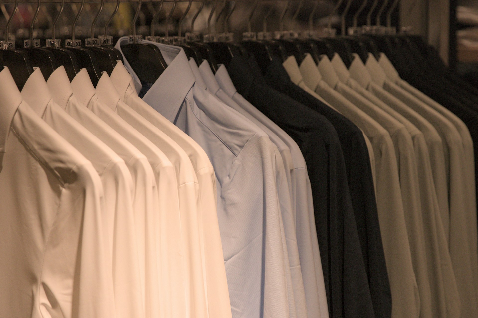 Shirts of various colors hang on hangers.